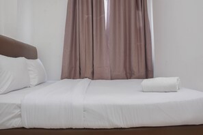A neatly made bed with white linens and a brown headboard, a white pillow, and a folded white towel on the bed. - Cozy Stay And Comfort 2Br At Bassura Apartment (Jakarta)