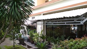 A courtyard with a koi pond, potted plants, and a pergola structure. - Cozy Furnished 3Br At Grand Setiabudi Apartment (Bandung)