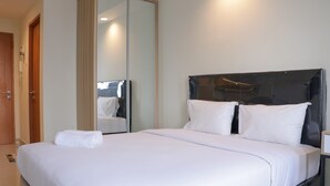 A hotel room with a large bed, a mirror, and a wooden door.