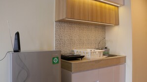 A compact kitchen with a refrigerator, a microwave, a sink, and a wooden cabinet above the countertop.