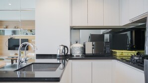 A modern kitchen with a black countertop, stainless steel appliances, and white cabinetry. - Well Designed And Cozy 2Br Apartment Branz Bsd City (Pagedangan)