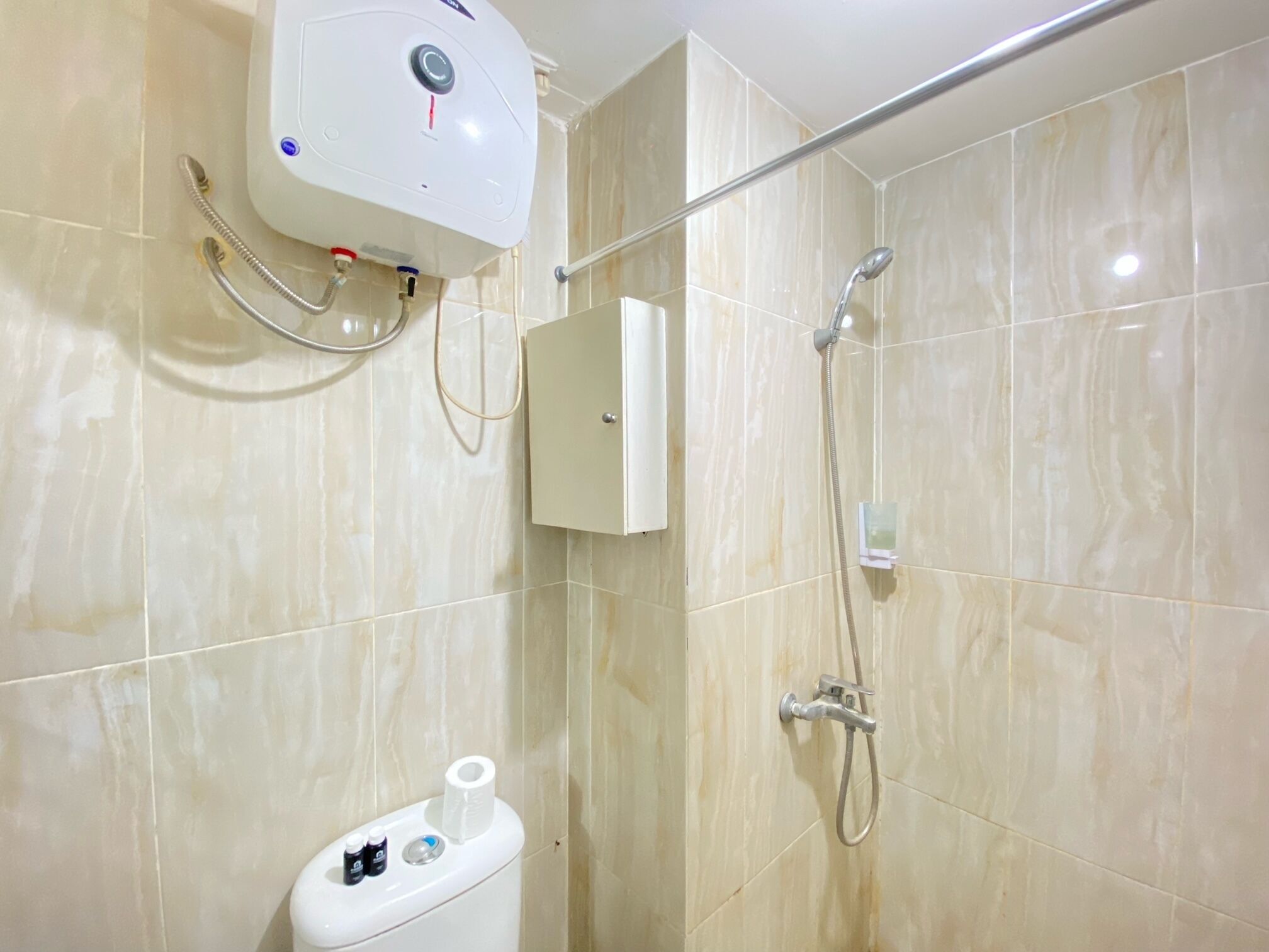 A bathroom with a toilet, a shower, and a water heater.