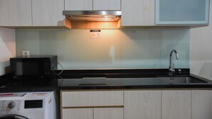 Eine Küche mit Mikrowelle, Waschmaschine und einer Spüle aus Edelstahl.