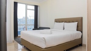 Ein Hotelzimmer mit einem großen Bett, Blick auf die Stadt durch das Fenster und ein Sessel am Fenster.