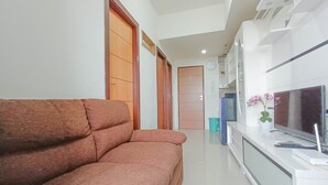 A modern living room with a sofa, a TV, and a white cabinet. - Nice And Homey 2Br At Vida View Makasar Apartment (Makassar)