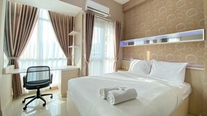 A hotel room with a bed, a desk, and a chair. - Cozy Studio Corner Room At Taman Melati Jatinangor Apartment (Hegarmanah)