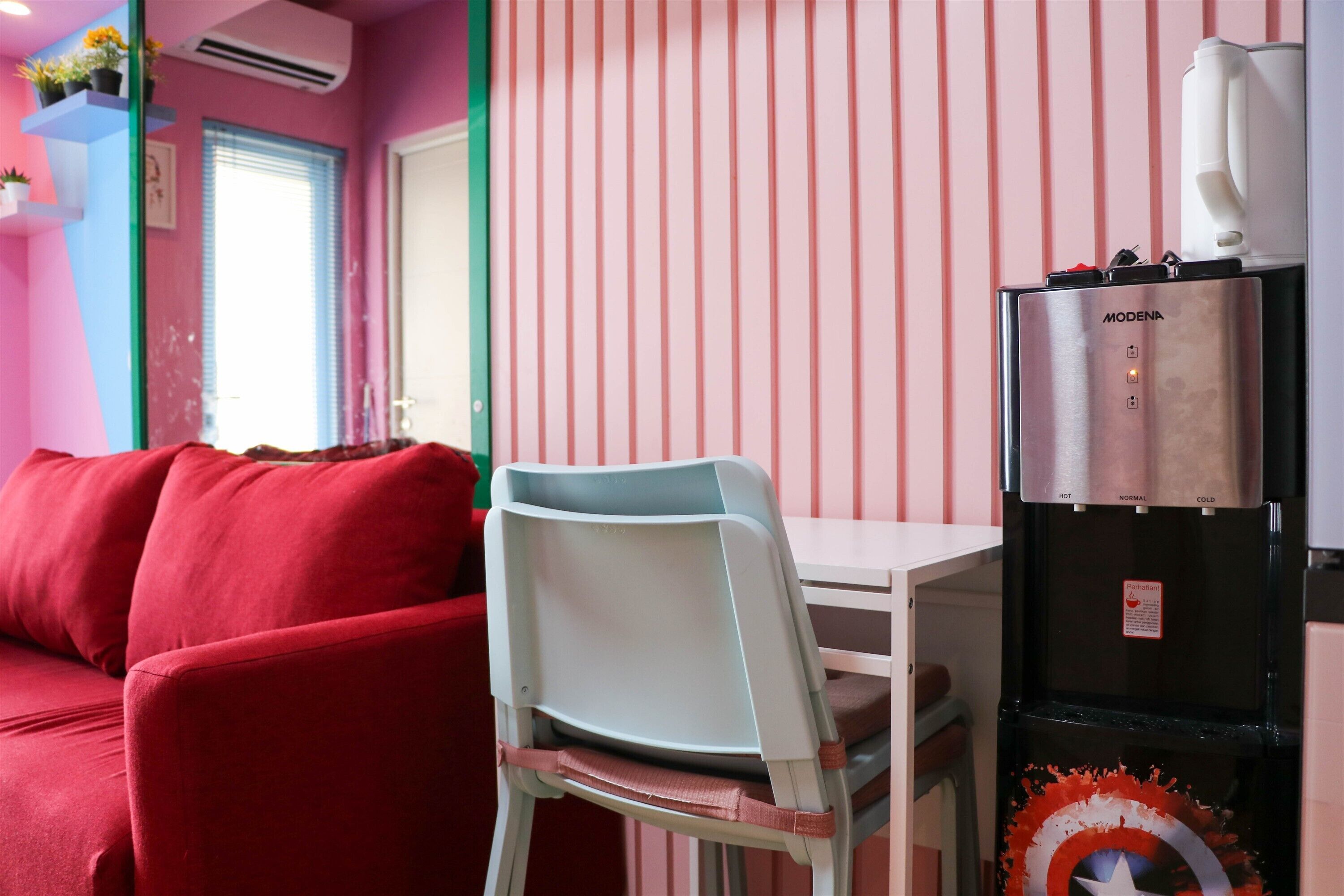 A room with a red sofa, a white chair, a black refrigerator, and a striped wall.