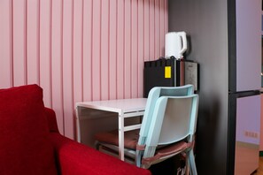 A compact room with a white desk, a red couch, and two light blue chairs. - Comfort And Cozy 2Br At Springlake Summarecon Bekasi Apartment (Bekasi)
