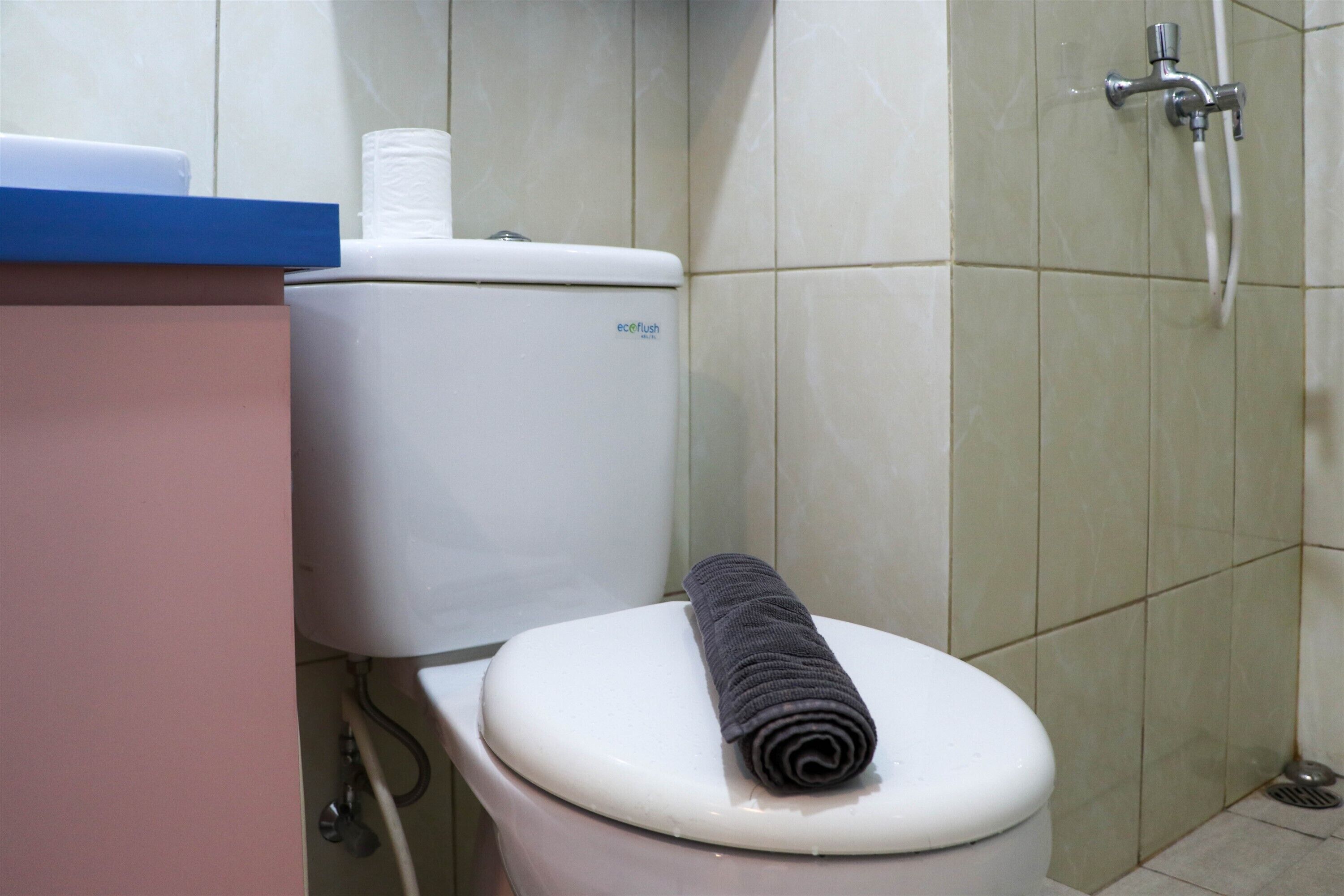 A bathroom with a toilet, a shower, and a towel on the toilet seat.