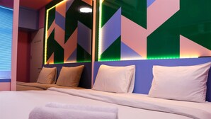 A modern hotel room with a large bed, multiple pillows, and a geometric-patterned wall. - Comfort And Cozy 2Br At Springlake Summarecon Bekasi Apartment (Bekasi)