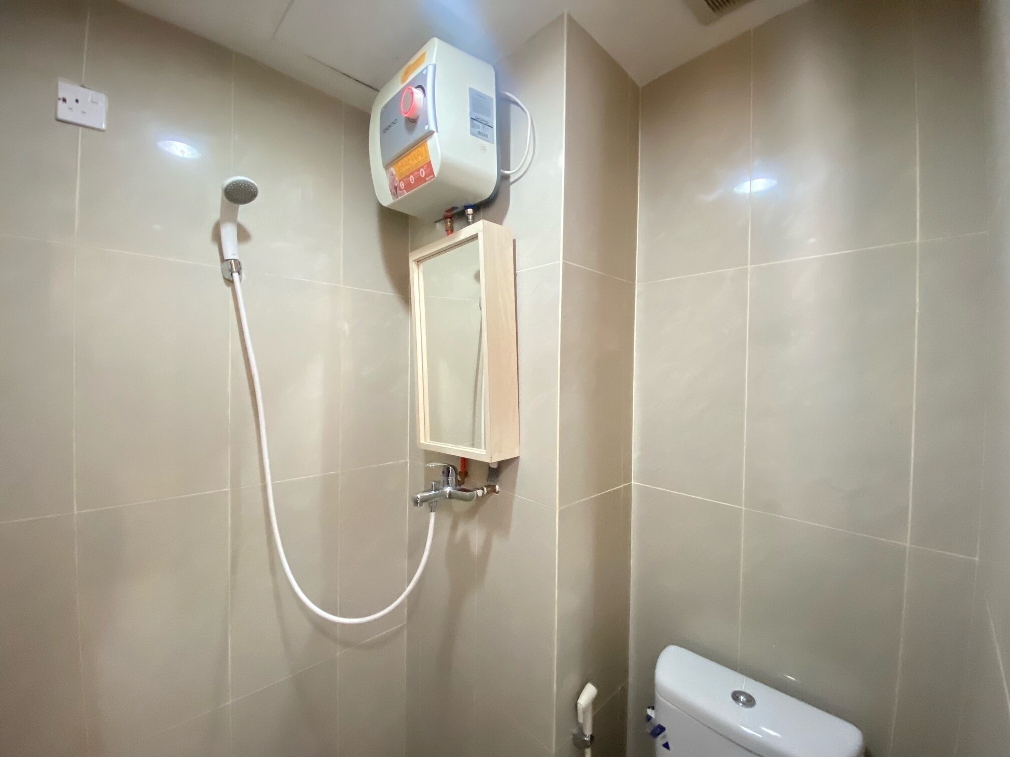 A bathroom with a shower, a toilet, and a wall-mounted heater.