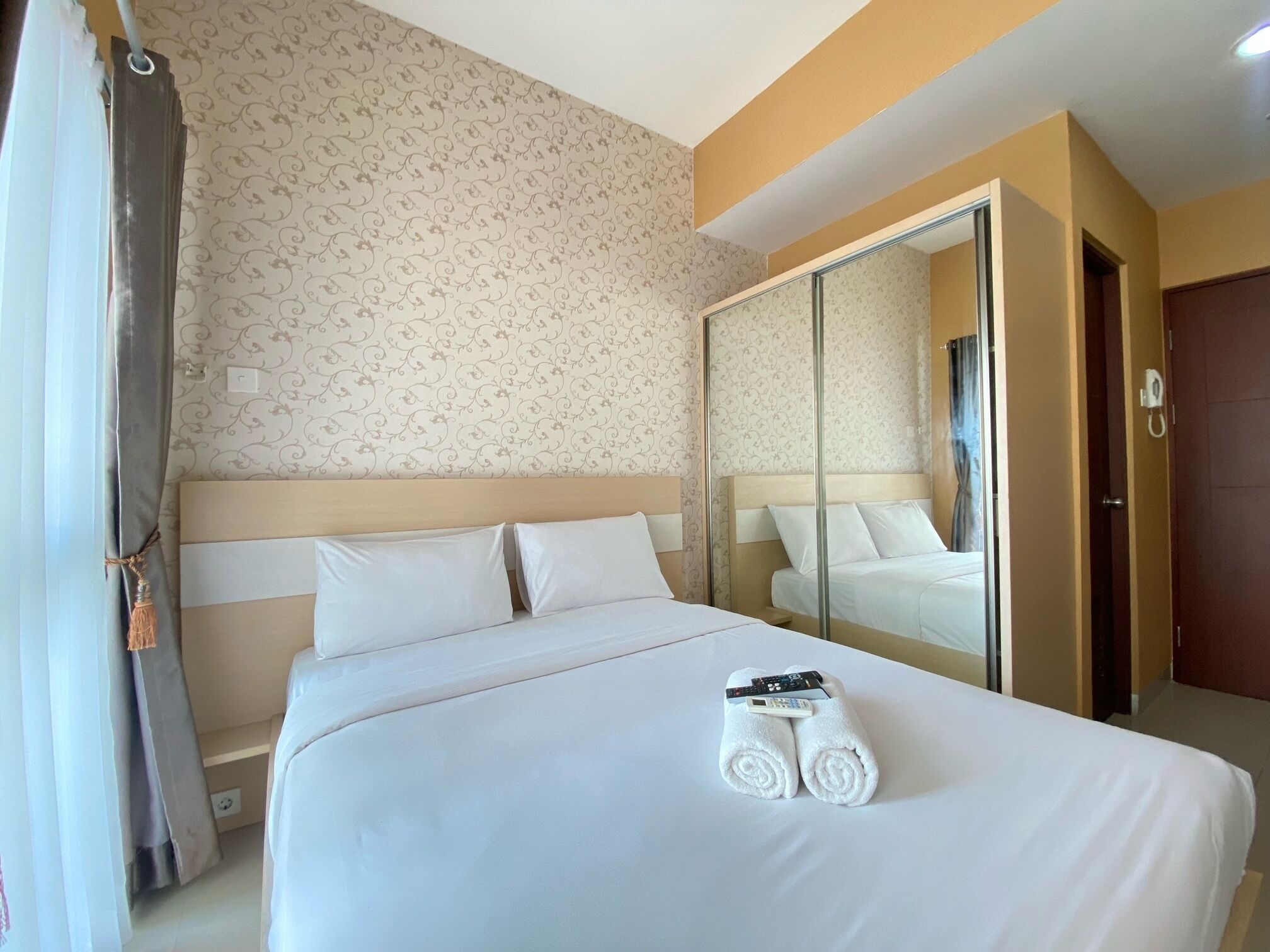 Een hotelkamer met een groot bed, een spiegel en een kledingkast.