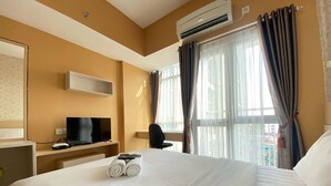 Une chambre d’hôtel avec un lit, une télévision, un bureau et une fenêtre avec des rideaux.