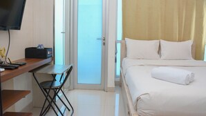 Ein Hotelzimmer mit Bett, Schreibtisch mit Stuhl, Fernseher und einer Tür zum Balkon.