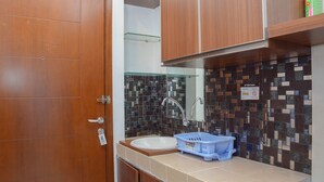 Ein Badezimmer mit Holztür, Waschbecken, Spiegel und einer Rückwand aus Mosaikfliesen.