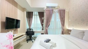 Une chambre d’hôtel avec un lit, un bureau et une chaise, une télévision et des rideaux.