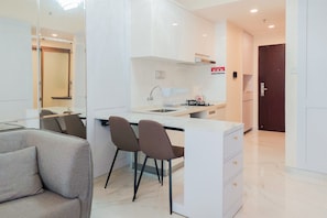 A modern kitchen with a central island, two bar stools, a built-in sink, and a dark wooden door.