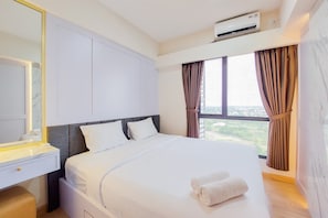 A hotel room with a bed, a bedside table, a mirror, and a window with curtains.