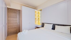 Habitación de hotel con una cama grande, una puerta de madera y un estante empotrado con iluminación.