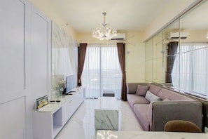 A modern living room with a sofa, TV, and a glass coffee table.