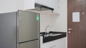 A kitchen with a stainless steel refrigerator, a black countertop, and white cabinets. - Nice And Modern Studio At Transpark Bintaro Apartment (South Tangerang)