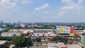 A commercial building with multiple storefronts, including a Courts building with a red and yellow sign. - Nice And Modern Studio At Transpark Bintaro Apartment (South Tangerang)