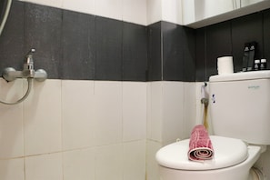 Une salle de bain équipée de toilettes, d’une douche et d’un porte-serviettes.