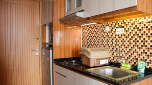Une cuisine de taille réduite, dotée de meubles en bois, d’un plan de travail noir, d’un évier et d’un crédence carrelée.
