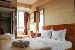 A hotel room with two beds, a wooden headboard, a large mirror, and a window with curtains. - Cozy And Simply Studio At Cinere Bellevue Suites Apartment (Depok)