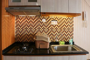 Uma cozinha com fogão a gás, pia, escorredor de louça e painel de azulejos.