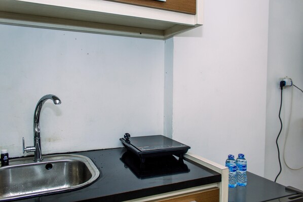 A kitchen with a stainless steel sink, a black countertop, and two water bottles.