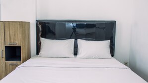 A bed with a headboard, a wooden wardrobe, and a wall socket. - Comfort Stay Studio Room At Poris 88 Apartment (Tangerang)