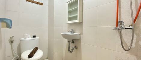 A small bathroom with a toilet, sink, and shower.