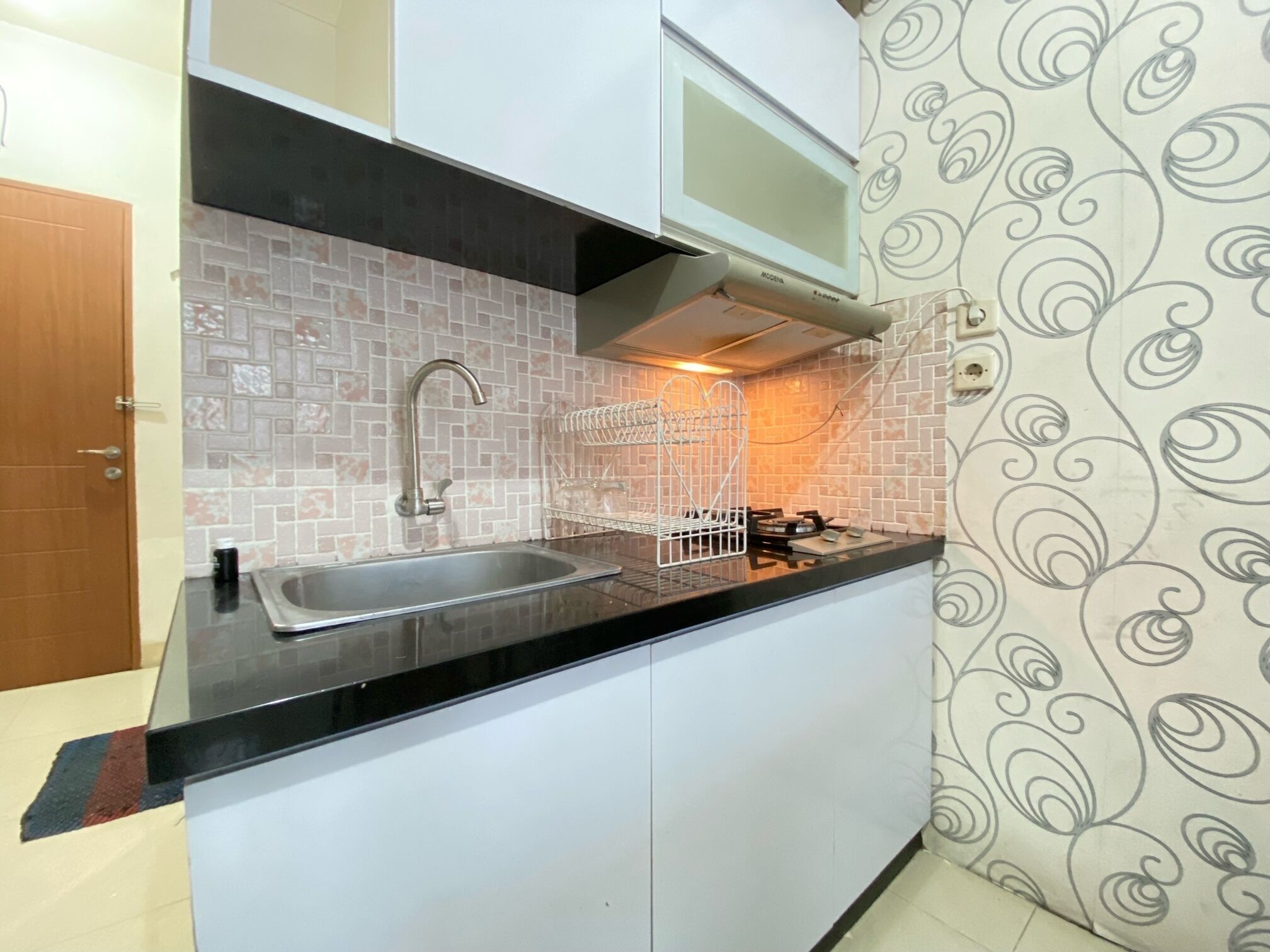 A compact kitchen with a sink, stove, and white cabinets.