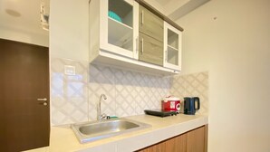 A modern kitchen with a stainless steel sink, wooden cabinets, and a microwave on the countertop. - Gorgeous 2Br Apartment At Mekarwangi Square Cibaduyut (Bandung)