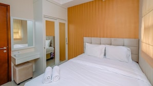 Ein Hotelzimmer mit Bett, Schminktisch mit Spiegel, Holz-Kopfteil und Kleiderschrank.