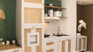 A kitchen with white cabinets, a sink, and a wooden countertop. - Minimalist Design Studio At Meikarta Apartment (Cikarang)