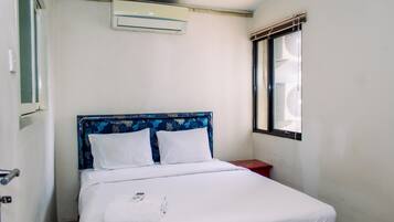 Uma cama de solteiro com cabeceira floral, roupa de cama branca e uma janela com vista para o exterior.