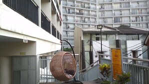 A balcony with a wicker chair, a potted plant, and a sign indicating a view of the sea. - Homey Furnished Studio At Beverly Dago Apartment (Bandung)