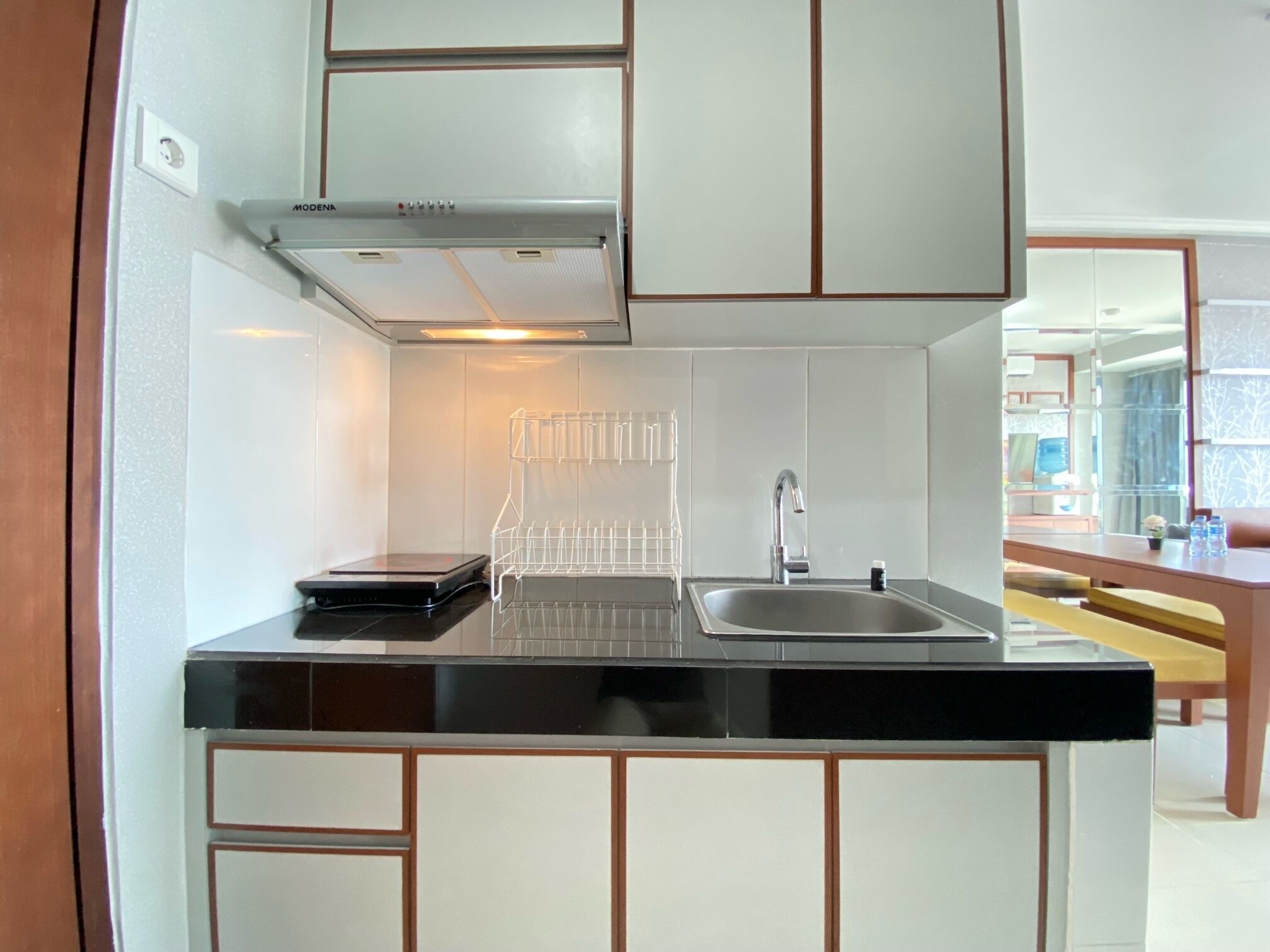 A modern kitchen with a black countertop, stainless steel sink, and white cabinets.