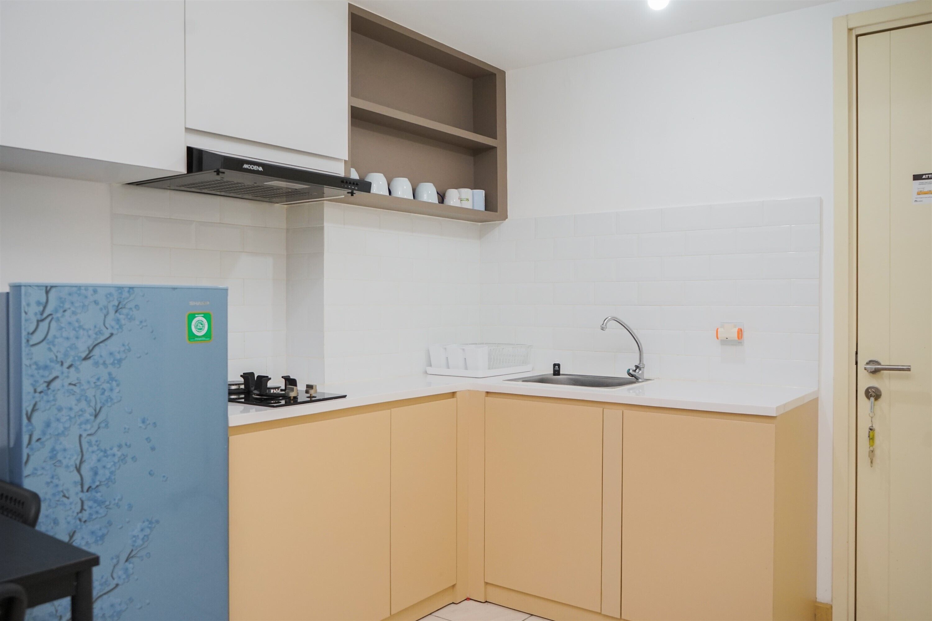 A compact kitchen with a built-in stove, a sink, and a small shelf above the counter.