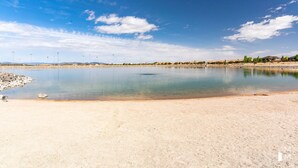 A calm lake with a sandy shore, surrounded by a clear blue sky and distant hills. - BRAND NEW The Townie (Cedar City)