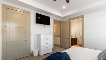 A bedroom with a bed, a dresser, a television, and a ceiling fan.