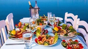 A table set for a meal with various dishes, glasses of water, and a bottle of champagne. - New Brand Villas,Heating Pool, Jacuzzi ,Spa near haraki beach,taverna,market (Charaki)