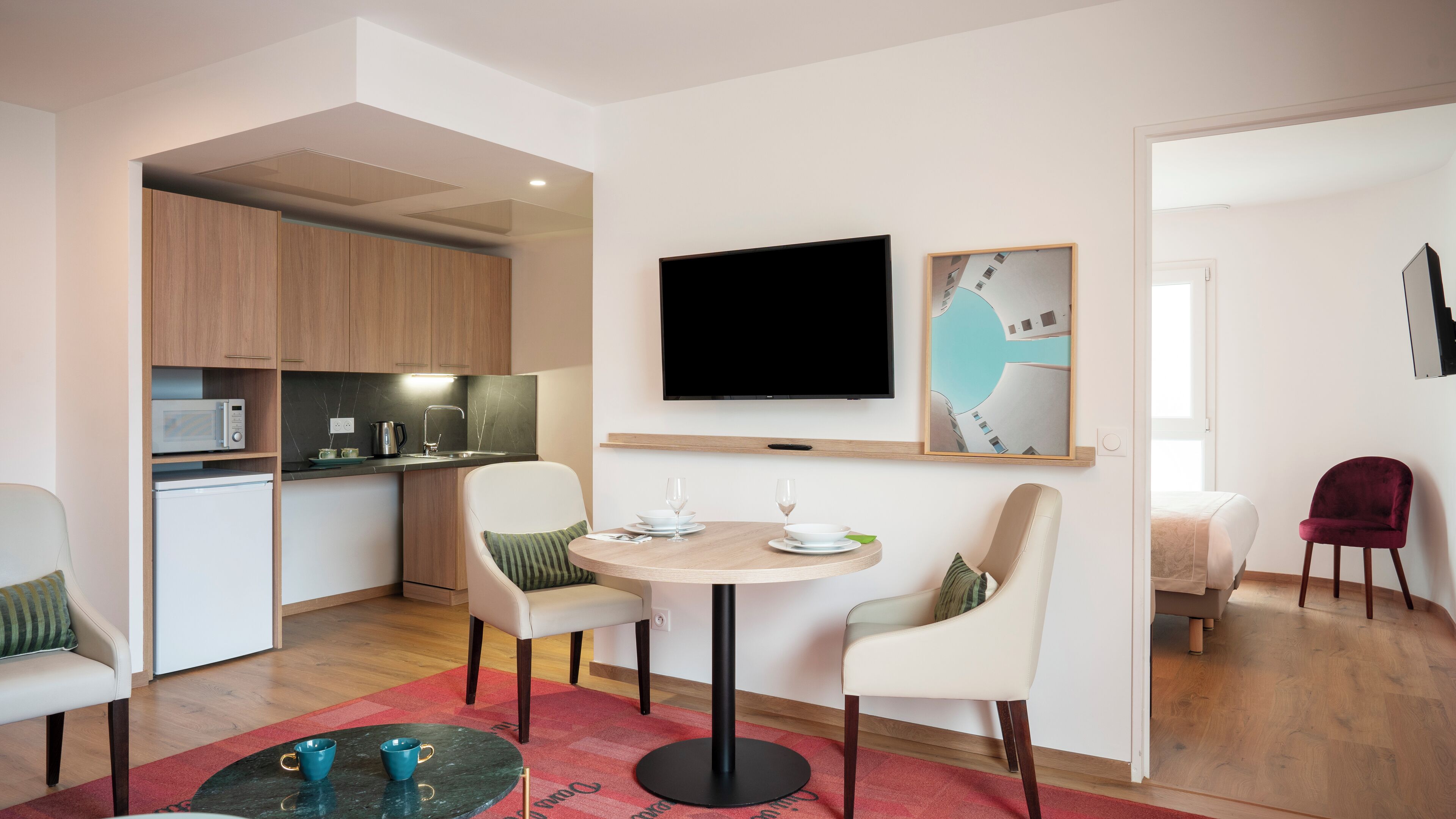 Un espacio habitable compacto con comedor, cocina y televisor instalado en la pared.