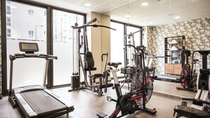A gym with cardio machines, weight stations, and a mirrored wall. - Residhome Quai d'Ivry (Ivry-sur-Seine)