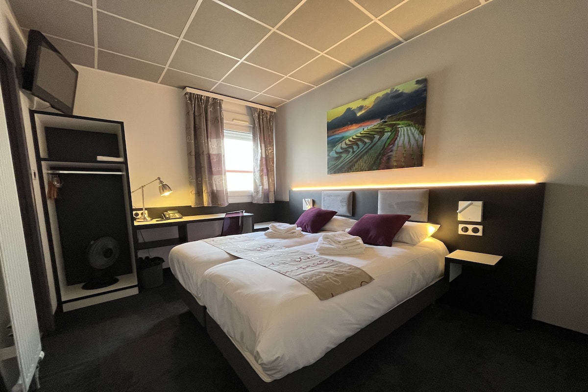 Ein modernes Hotelzimmer mit einem großen Bett, einem Schreibtisch und einem Gemälde an der Wand.