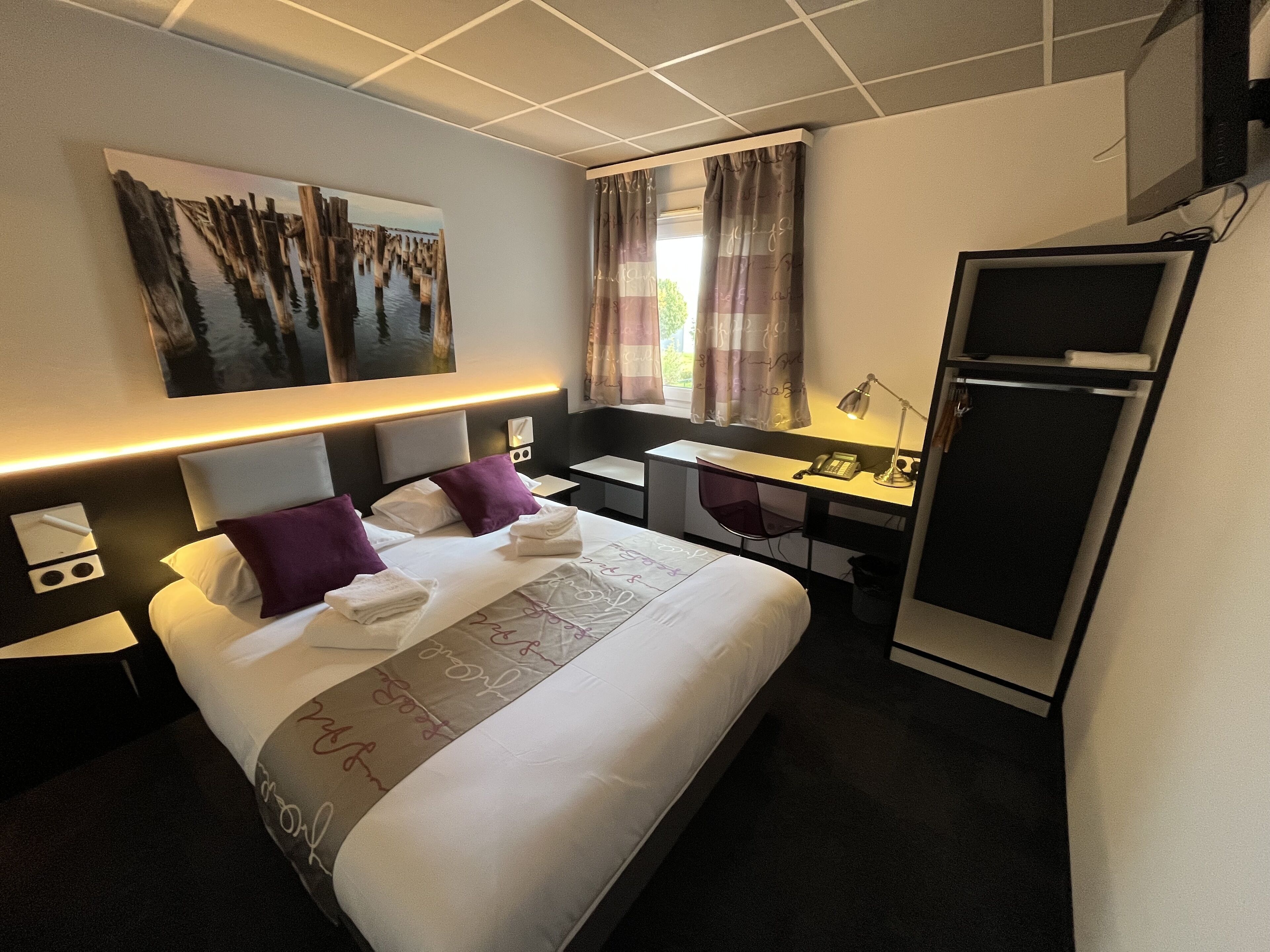 Habitación de hotel con cama, escritorio y refrigerador.