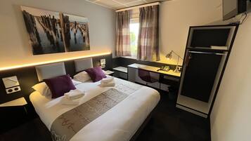 Habitación de hotel con cama, escritorio y refrigerador.