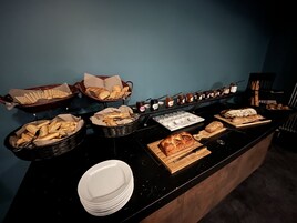 Buffet com diversos pães, doces e acompanhamentos.